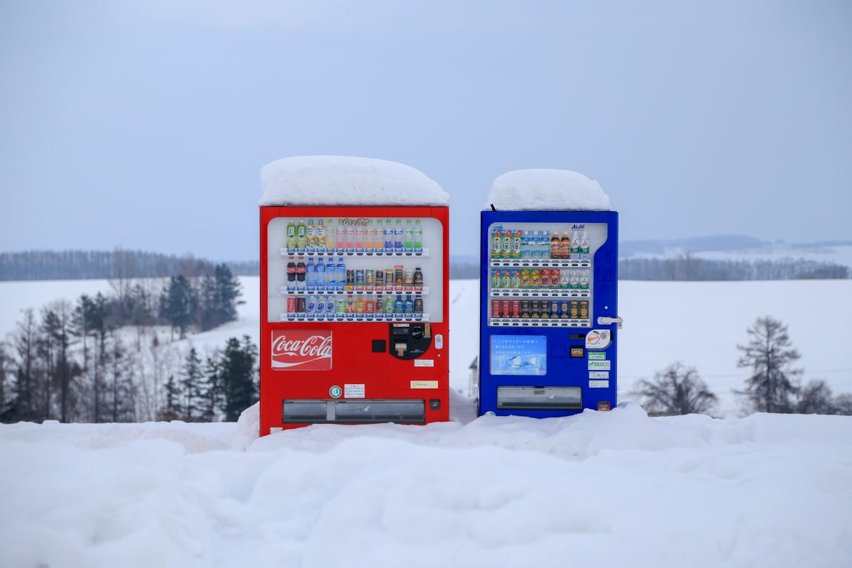Rows of colorful vending machines on a street in Japan offering drinks and snacks.