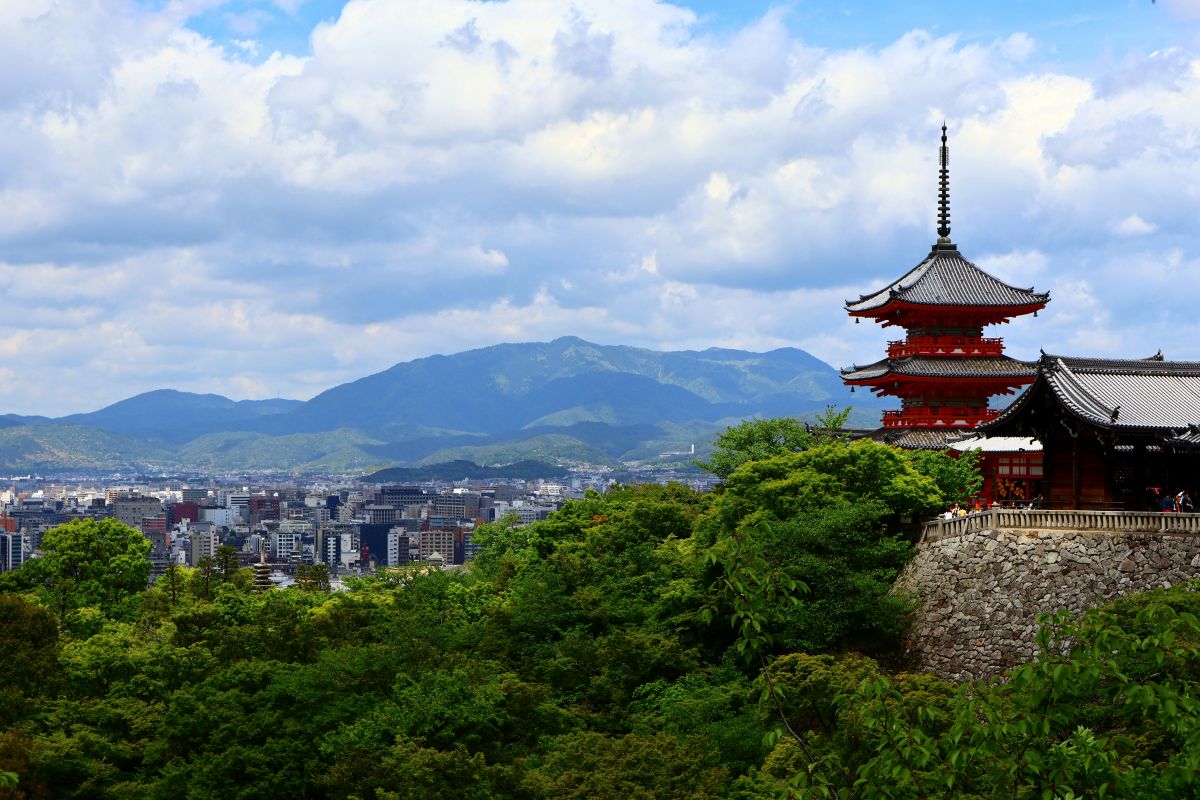 A peaceful Japanese landscape with mountains, trees, and a traditional shrine