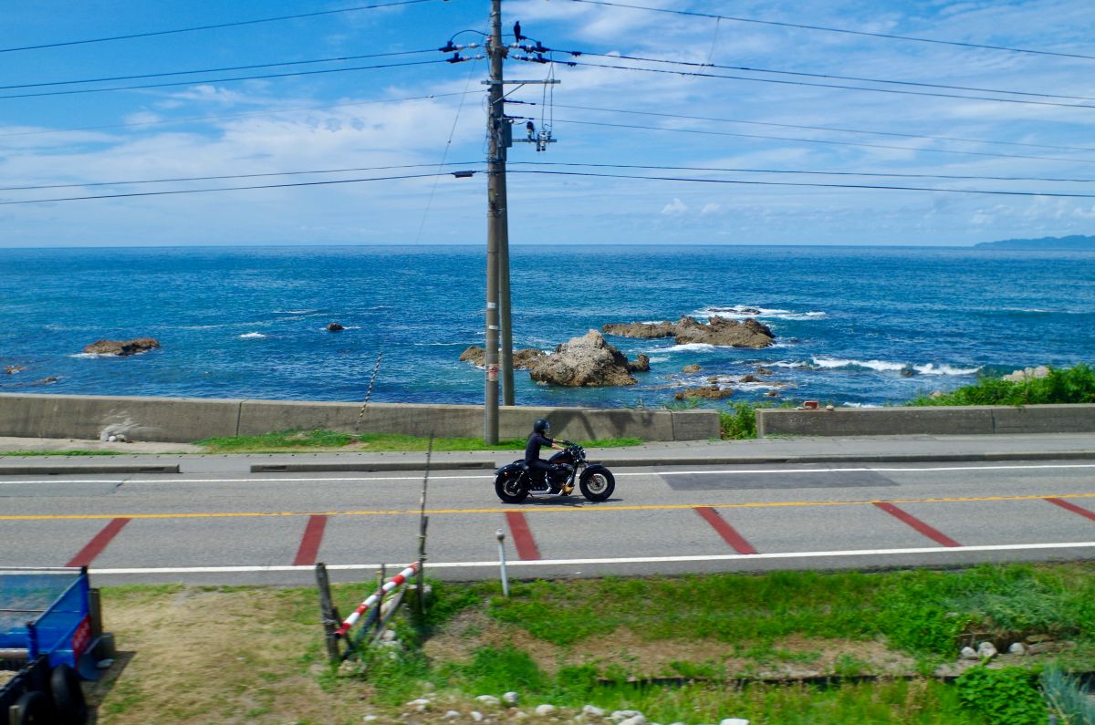 Car traveling along a scenic coastal road with ocean views in Japan