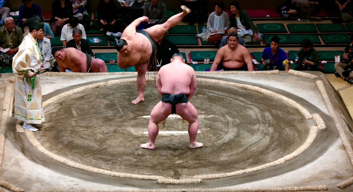 Two sumo wrestlers competing inside a traditional sumo ring during a professional tournament in Japan