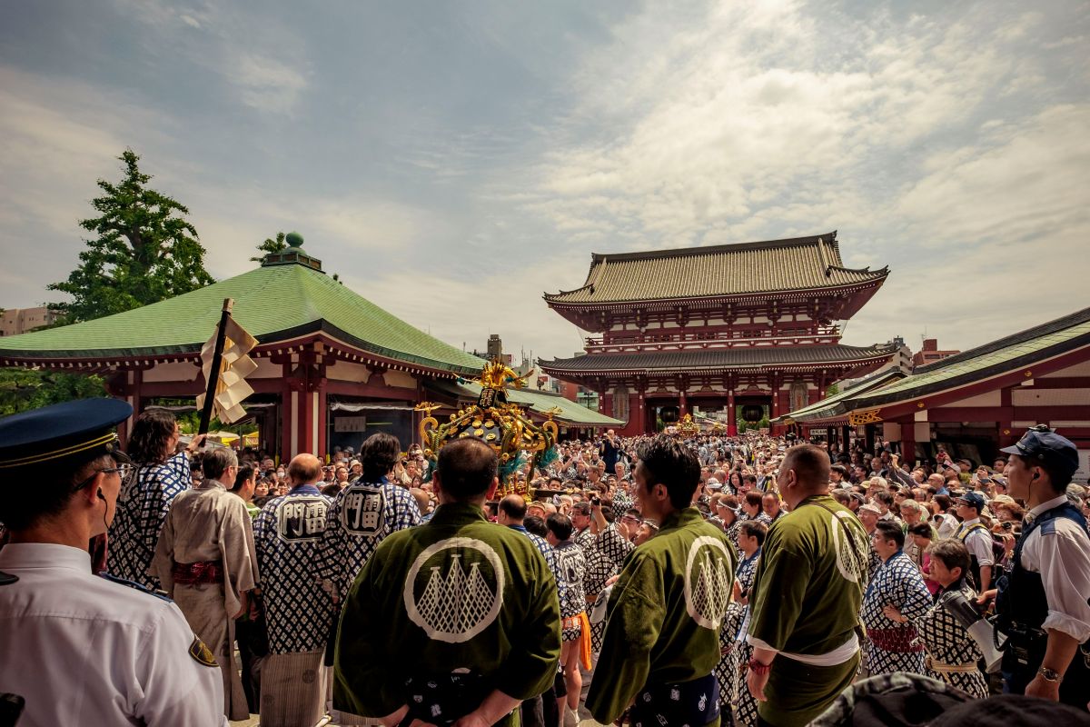 People wearing yukata and enjoying food stalls at a traditional Japanese summer festival.