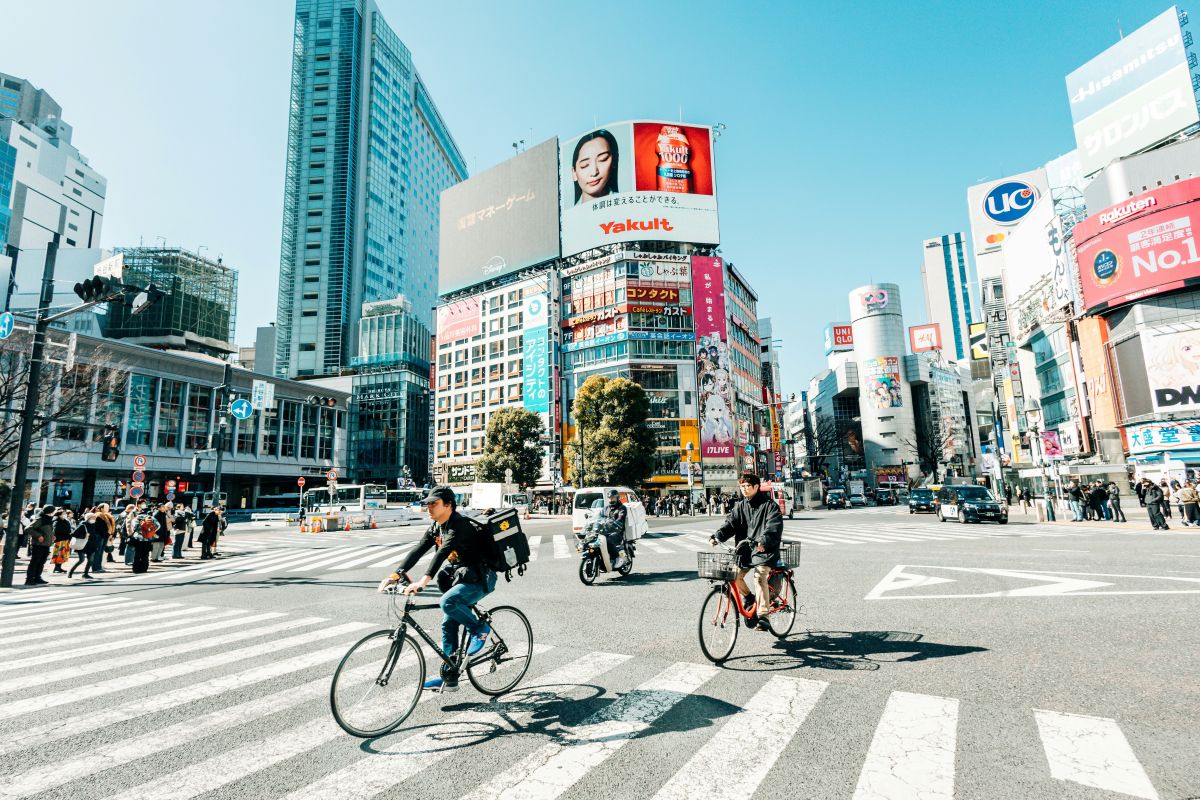People riding bicycles carefully along a residential street in Japan.