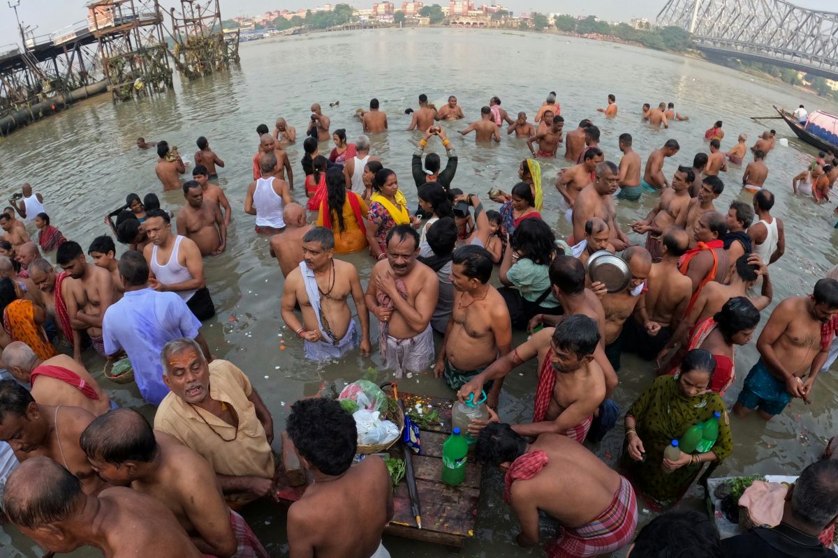インドの湖岸で衣類を岩に打ちつけながら洗濯する様子。