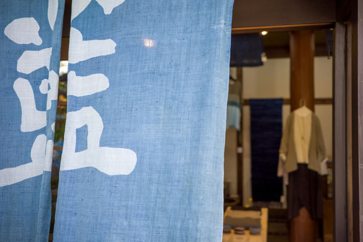 Traditional indigo dyeing workshop in a historic Japanese village with blue-dyed fabrics hanging outside