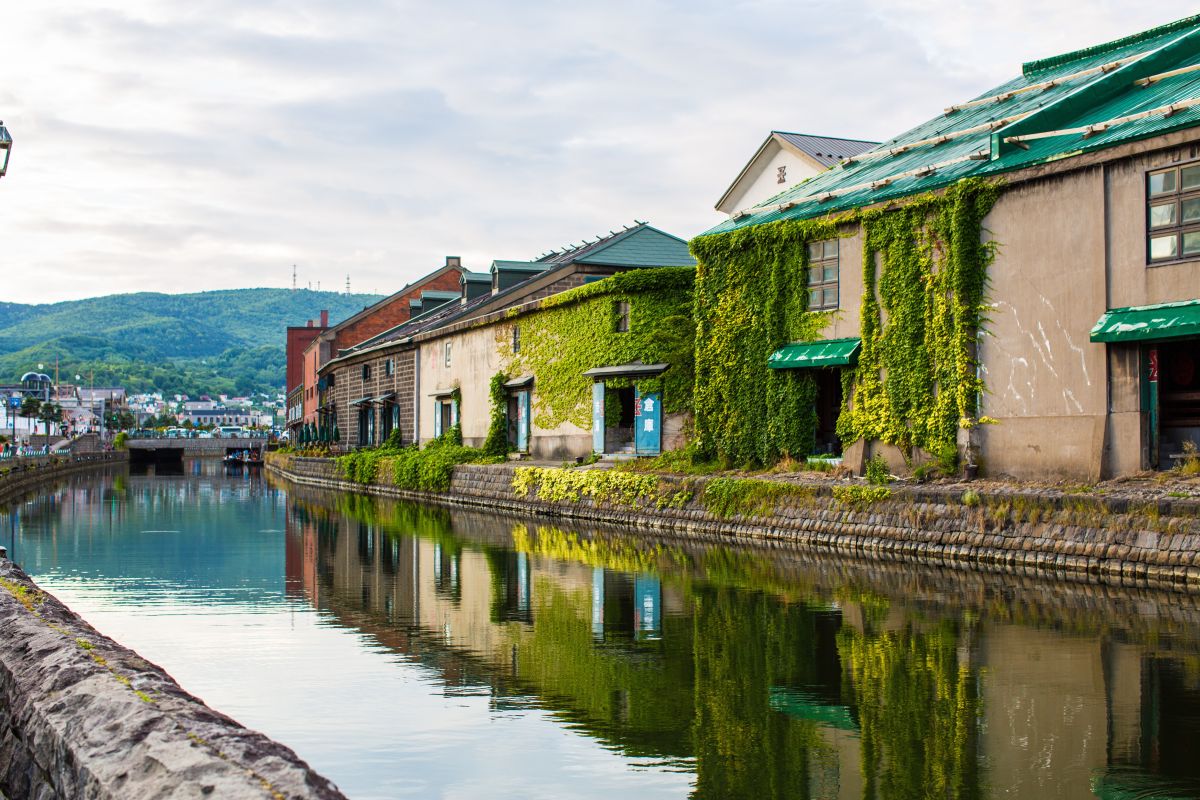 Historic Japanese port town with traditional buildings and fishing boats beside a calm harbor